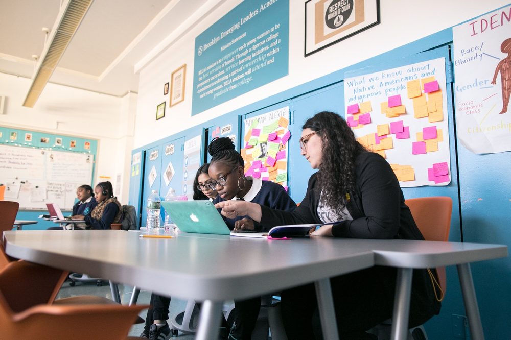 A teacher and students working together at a laptop